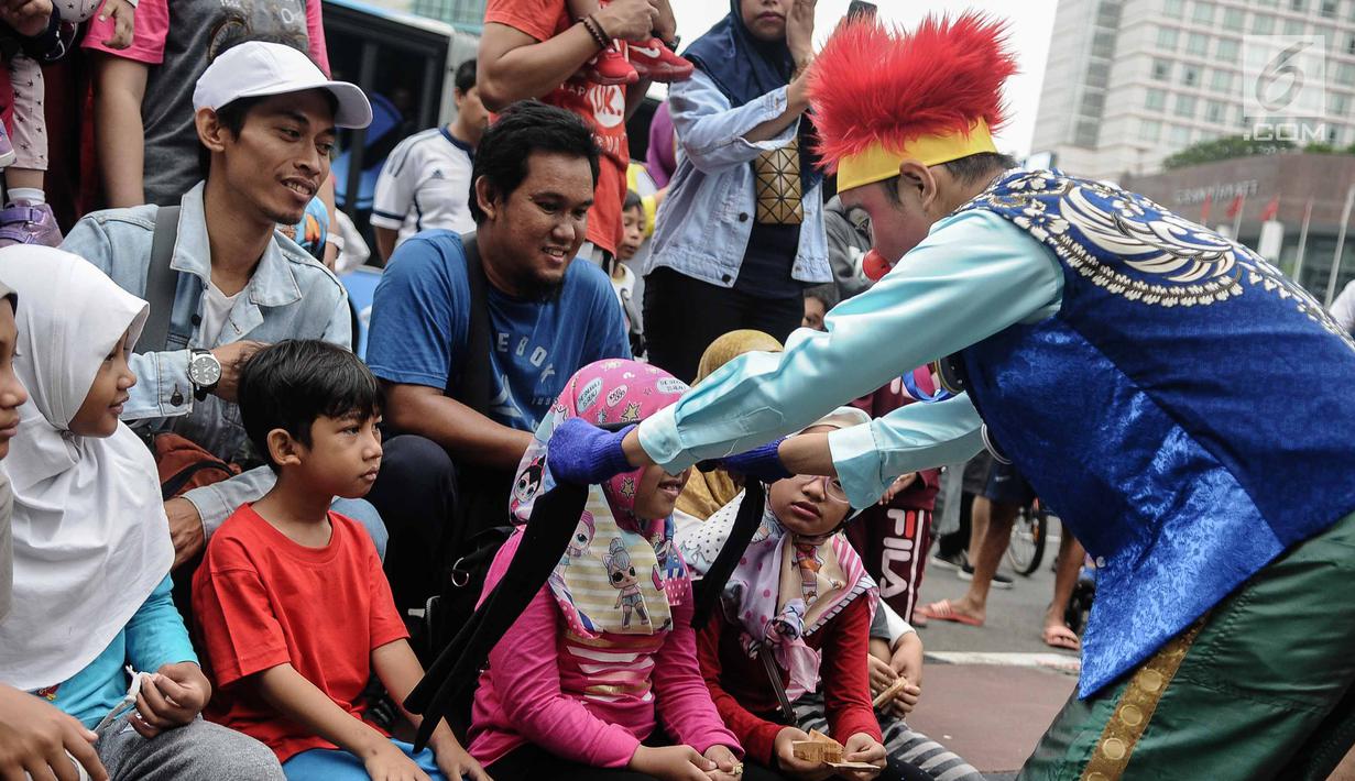 Badut yang tergabung dalam Aku Badut Indonesia mengajak bermain seorang anak saat car free day di Bunderan HI, Jakarta, Minggu (9/12). Aksi tersebut bentuk kampanye positif bertujuan mengajak masyarakat peduli terhadap sesama. (Liputan6.com/Faizal Fanani)