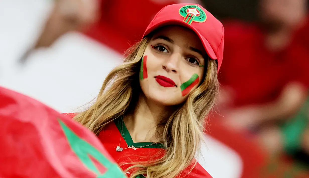 Fans Maroko tersenyum saat menyaksikan laga Maroko melawan Spanyol pada laga Piala Dunia 2022 di Stadion Education City, Selasa (6/12/2022). (AFP/Jack Guez)