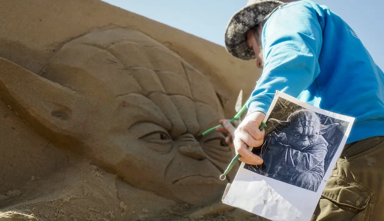 Seorang seniman patung saat membuat patung dari pasir yang berbentuk seperti pemeran Yoda dalam film Star Wars di Kazakhstan , 15 April 2016. Kebanyakan patung yang dibuat terinspirasi dari film - film Hollywood. (REUTERS / Shamil Zhumatov)