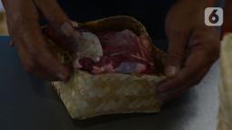 Petugas memasukan daging ke besek di Rumah Pemotongan Hewan (RPH) Dharma Jaya, Jakarta, Rabu (21/7/2021). Dimana RPH Dharma Jaya menerima pemotongan sebanyak 600 ekor sapi dengan penerapan protokol kesehatan saat penyembelihan dengan tes swab sebelum bekerja.  (merdeka.com/Imam Buhori)