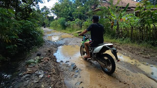 Warga Kecamatan Patia, Kabupaten Pandeglang, Banten, Melintasi Jalan Rusak Di Desanya. (Rabu, 02/12/2020). (Yandhi Deslatama/Liputan6.com)