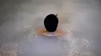 Seorang pria bersantai dalam kolam renang indoor di pemandian air panas Jepang atau onsen di Yokohama, prefektur Kanagawa pada 29 Mei 2020. Dengan pencabutan status darurat nasional pada Senin (25/5) lalu, banyak bisnis yang mulai beroperasi kembali tak terkecuali dengan onsen. (Behrouz MEHRI/AFP)