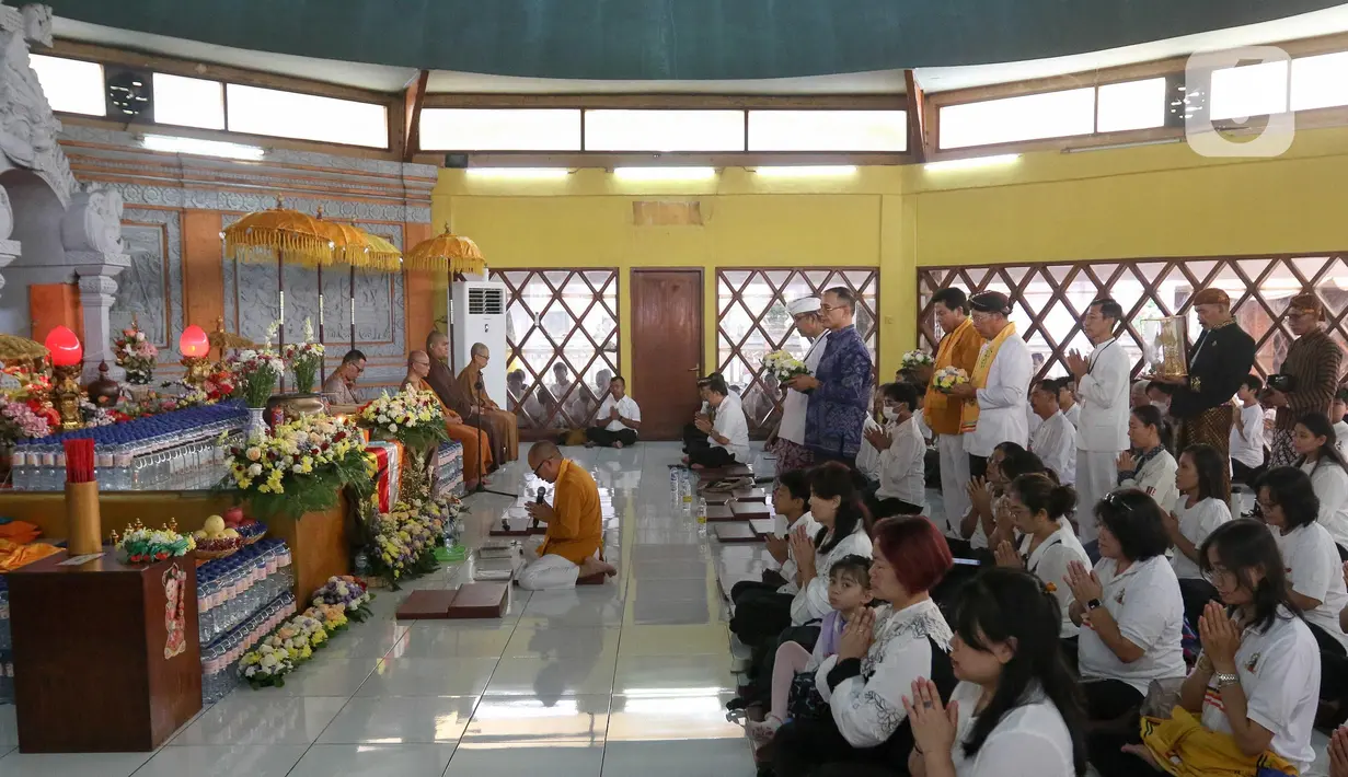 Umat Buddha mengikuti prosesi Puja Bakti di Wihara Arya Dwipa Arama, Taman Mini Indonesia Indah (TMII), Jakarta, Senin (12/5/2025). (Liputan6.com/Herman Zakharia)