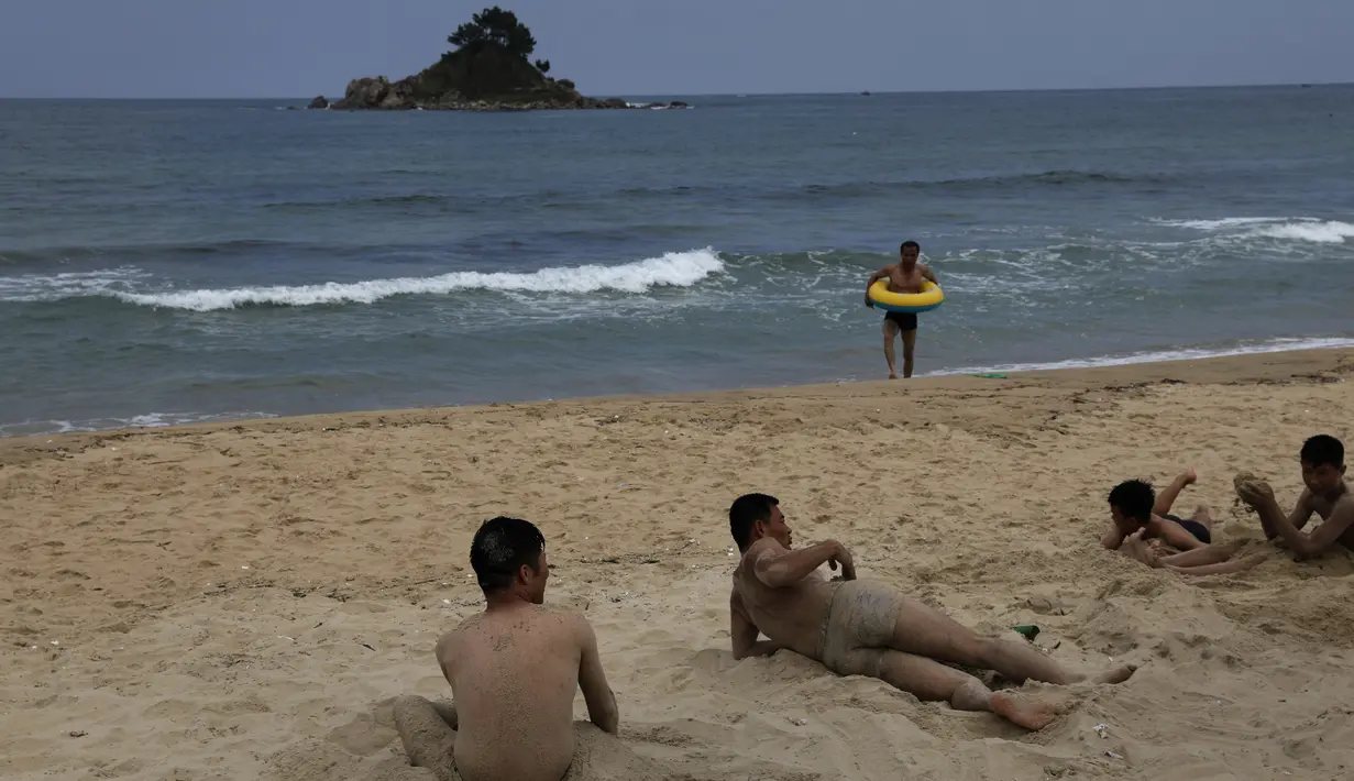 Sejumlah pria bermain pasir saat menikmati akhir pekan di pantai Sijung Ho di Korea Utara (14/7/2019). Pantai Sijung Ho merupakan tujuan wisata populer bagi penduduk lokal dan asing. (AP Photo/Vincent Yu)