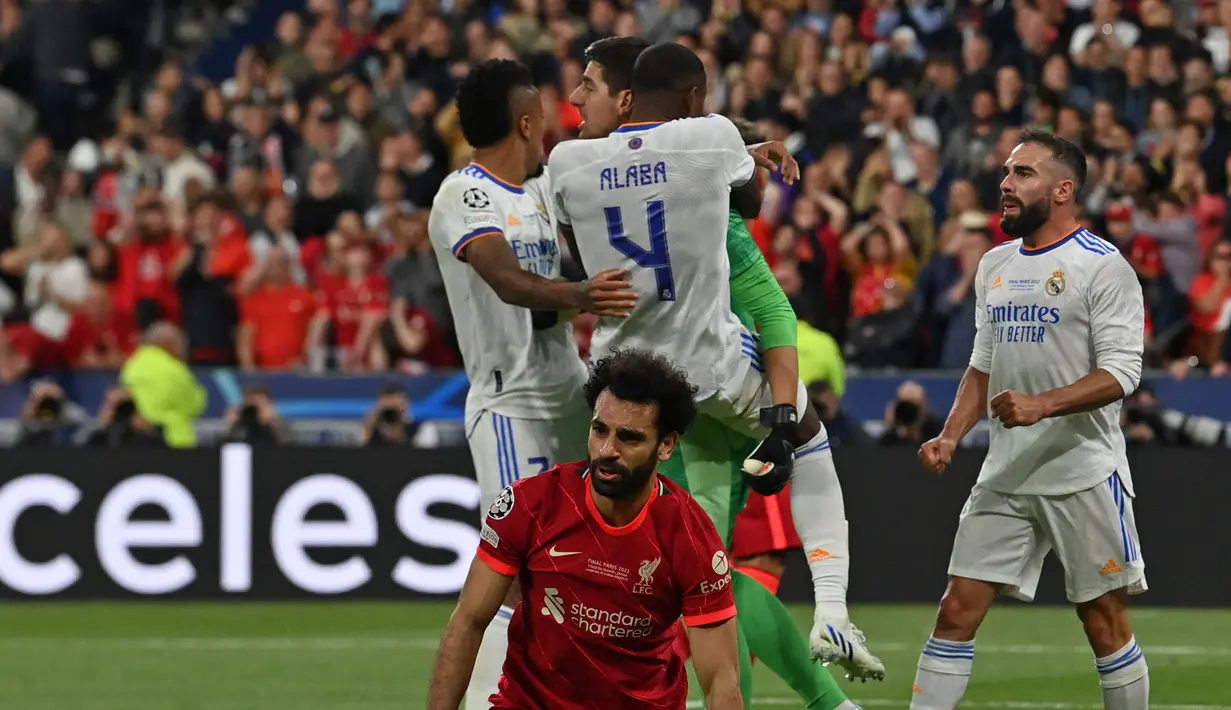 <p>Kiper Real Madrid, Thibaut Courtois (tengah) melakukan selebrasi bersama rekannya usai berhasil menepis tendangan dari pemain Liverpool, Mohamed Salah saat laga final Liga Champions antara Liverpool melawan Real Madrid yang berlangsung di Stade de France, Saint Denis, Sabtu, 28 Mei 2022 waktu setempat. (AFP/Paul Ellis)</p>