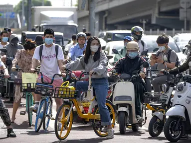 Para komuter yang mengenakan masker menunggu di persimpangan kawasan pusat bisnis di Beijing, China, Selasa (31/5/2022). Otoritas Shanghai mengatakan mereka akan mengambil beberapa langkah besar pada Rabu untuk membuka kembali kota terbesar di China setelah dua bulan penguncian COVID-19. (AP Photo/Mark Schiefelbein)