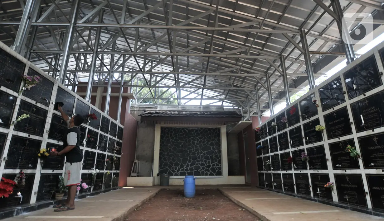 Penjaga membersihkan makam bersusun atau kolumbarium di kompleks pemakaman Paroki Gereja St Servatius, Kampung Sawah, Bekasi, Jawa Barat, Kamis (26/12/2019). Pembangunan kolumbarium di tempat tersebut dilakukan akibat keterbatasan lahan. (merdeka.com/Iqbal Nugroho)