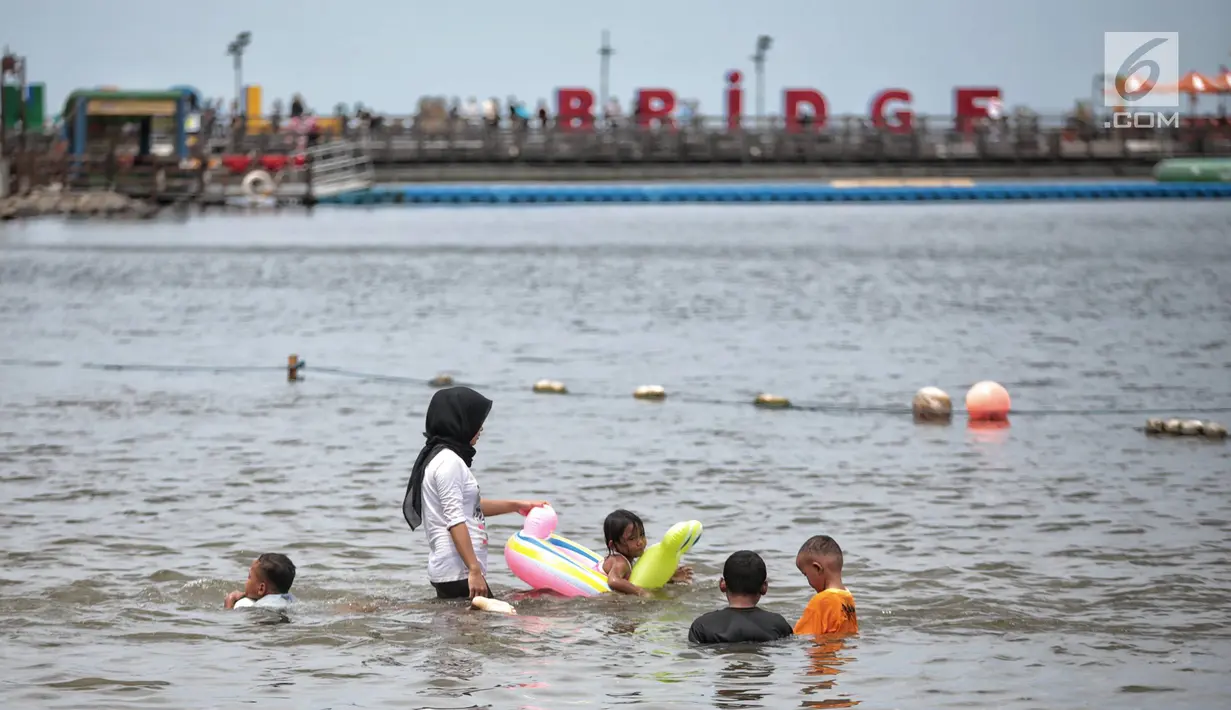 Sejumlah anak berenang di Beach Pool Ancol, Jakarta, Selasa (25/12). Pasangnya air laut dan cuaca buruk mengakibatkan pantai Ancol sepi pengunjung saat libur Natal 2018. (Liputan6.com/Faizal Fanani)
