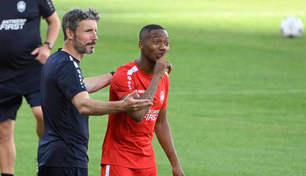 Pelatih Antwerp FC, Mark van Bommel, memberikan arahan kepada Michel-Ange Balikwisha saat sesi latihan jelang laga Liga Champions di Estadi Olimpic Lluis Companys, Barcelona, Senin (19/9/2023). Antwerp FC akan berhadapan dengan Barca. (AFP/Josep Lago)
