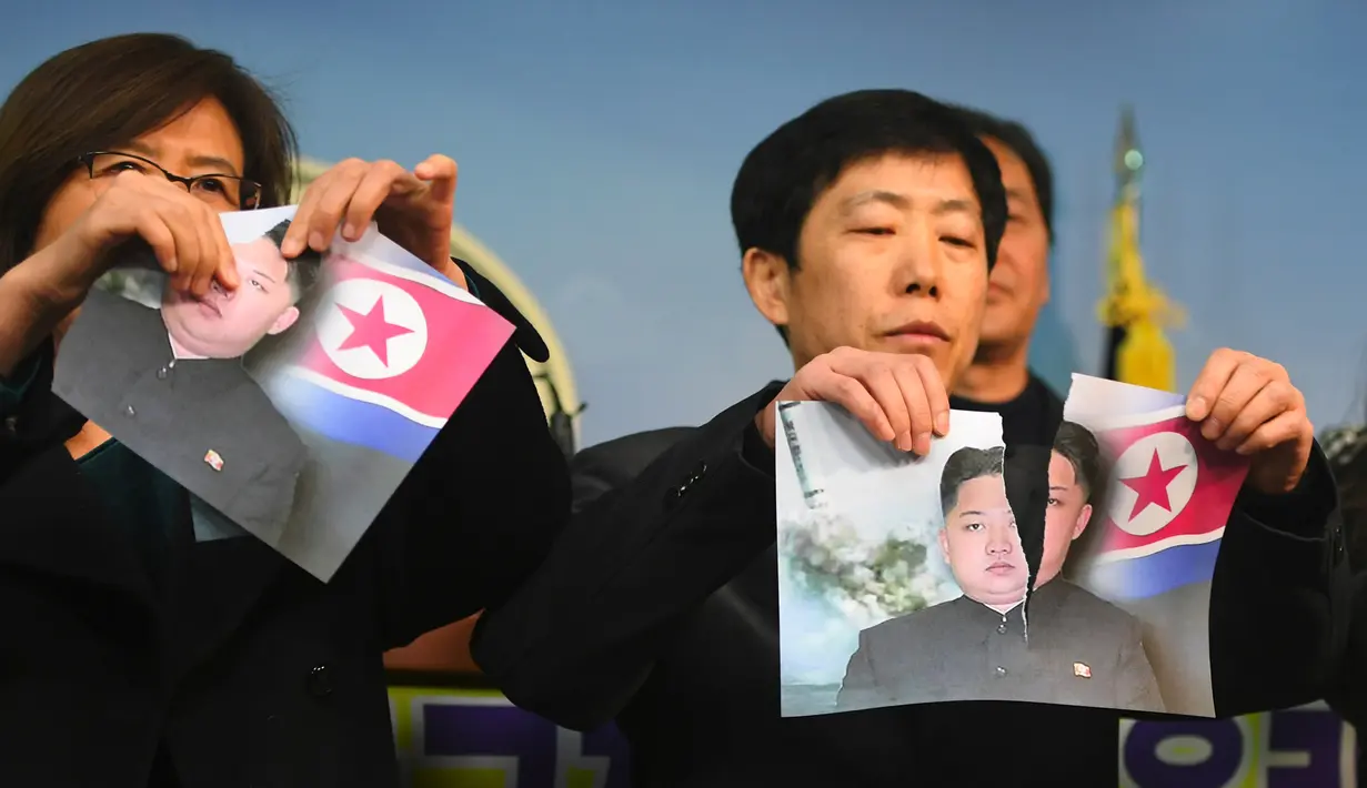 Warga Korea Utara yang membelot menunjukkan foto pemimpin Korea Utara Kim Jong-Un yang dirobek saat konferensi pers di Majelis Nasional di Seoul (24/1). (AFP Photo/Jung Yeon-Je)