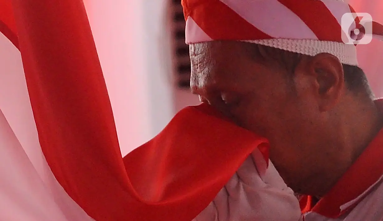Ekspresi seorang warga binaan narapidana terorisme (napiter) saat mencium bendera Merah Outih pada acara ikrar dan janji setia Negara Kesatuan Republik Indonesia (NKRI) di Lapas Narkotika Kelas IIA, Gunung Sindur, Bogor, Jawa Barat, Kamis (1/6/2023). (merdeka.com/Arie Basuki)