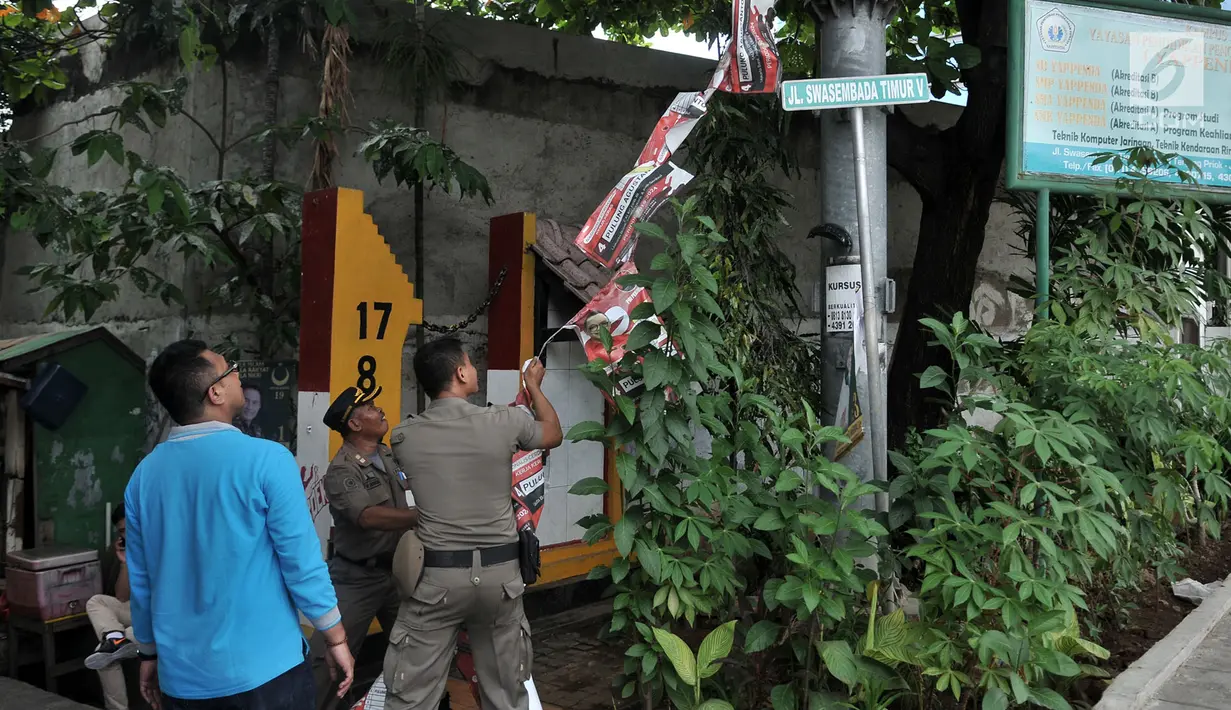 Panitia Pengawas Pemilu (Panwaslu) bersama Satpol PP mencopot spanduk Calon Legislatif saat penertiban Alat Peraga Kampanye (APK) di sepanjang Jalan Yos Sudarso, Jakarta Utara, Rabu (13/3). (merdeka.com/Iqbal S. Nugroho)