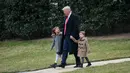 Presiden AS, Donald Trump berjalan bersama cucunya, Arabella dan Joseph Kushner menuju Marine One saat berangkat ke Carolina Selatan dari Gedung Putih, di Washington, AS, (17/2). (AFP Photo/ Mandel Ngan)