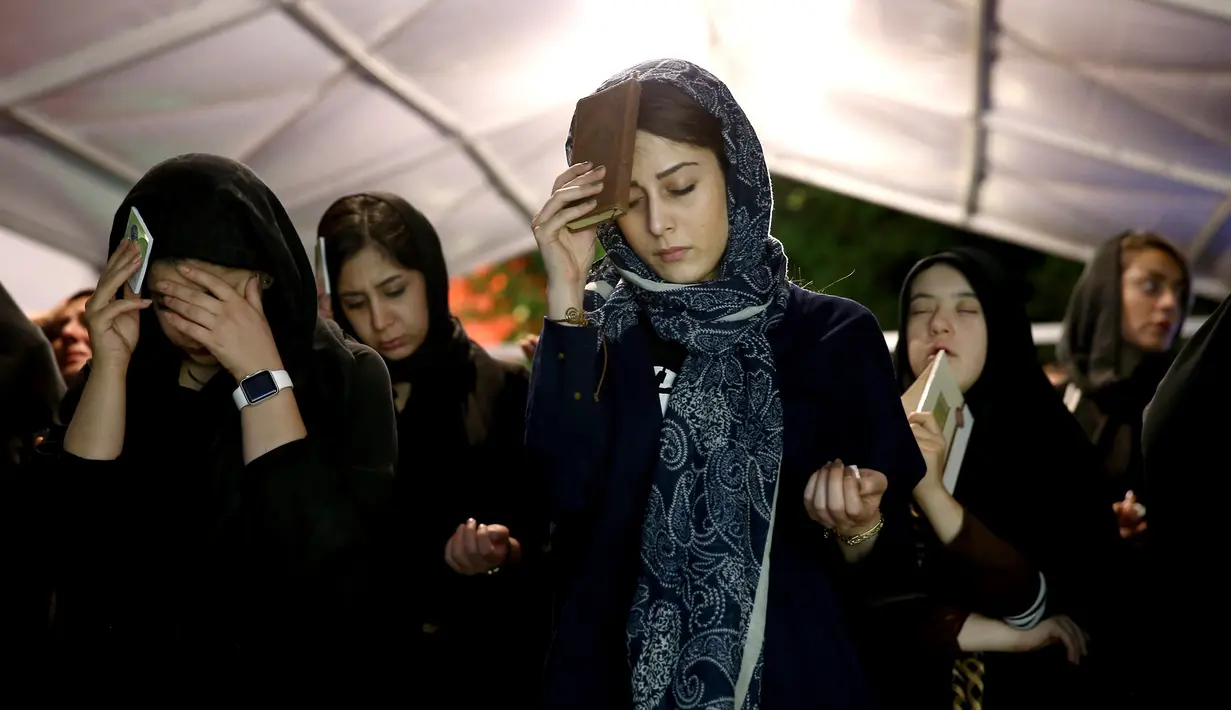 Muslim Syiah Iran meletakkan mushaf Alquran di kepala mereka saat berburu malam Lailatul Qadar di Teheran, Iran, Jumat (8/6). Mereka berkumpul untuk meminta pengampunan dan membuat harapan di malam Lailatul Qadar. (AP Photo/Ebrahim Noroozi)