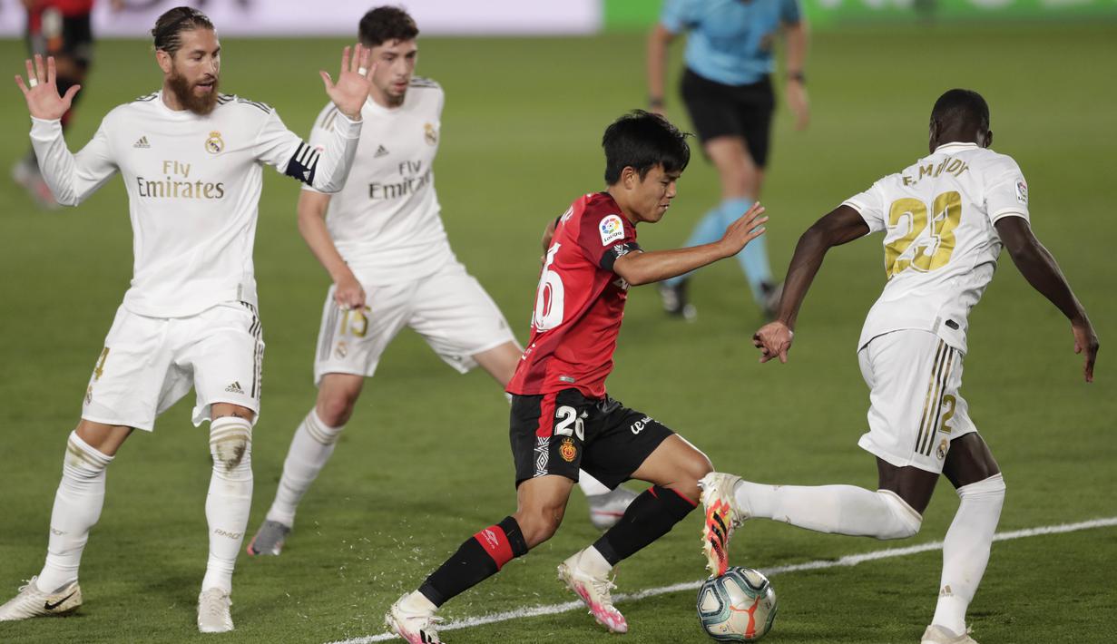 Pemain Real Mallorca, Takefusa Kubo, berusaha melewati pemain Real Madrid pada laga La Liga di Stadion Alfredo Di Stefano, Kamis (25/6/2020). Real Madrid menang 2-0 atas Real Mallorca. (AP/Bernat Armangue)