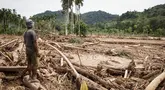 Seorang pria melihat kerusakan yang disebabkan oleh banjir yang membawa sisa-sisa pembalakan liar di Pelangai Gadang, Sumatera Barat, pada Sabtu 15 Maret 2025. (REZAN SOLEH/AFP)