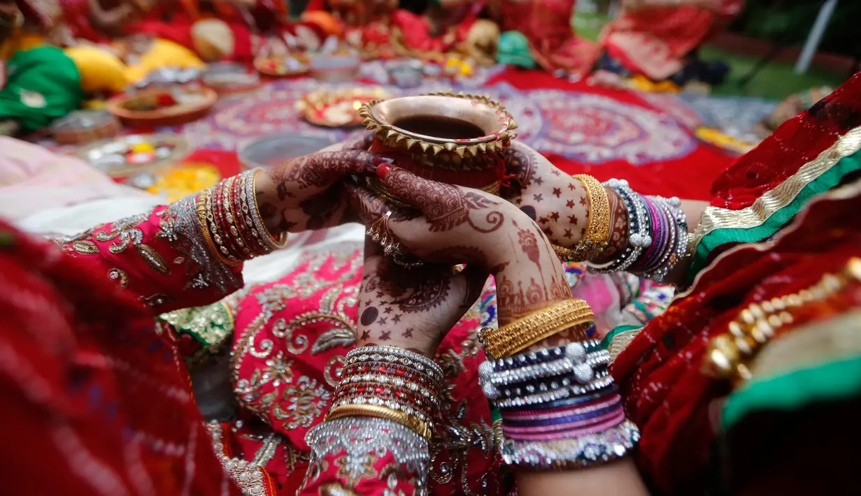 Wanita Hindu yang sudah menikah melakukan ritual festival Karva Chauth di Ahmadabad,  Kamis (17/10/2019). Selama festival Karva Chauth, wanita-wanita yang sudah menikah di India berpuasa sepanjang hari dan memohon umur panjang serta keselamatan untuk suami mereka. (AP/Ajit Solanki)