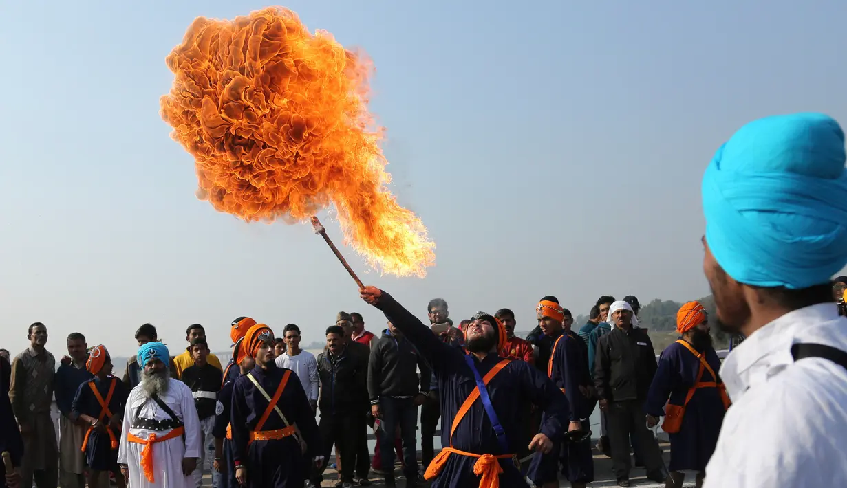 Seorang prajurit Sikh India menyemburkan api saat menampilkan atraksi selama prosesi keagamaan menjelang ulang tahun kelahiran Guru Gobind Singh di Jammu, India (2/1). (AP Photo / Channi Anand)