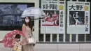 Warga Jepang mengenakan masker berjalan melewati poster yang berisi informasi peraih medali emas dari Jepang di Olimpiade Tokyo, Selasa (27/7/2021). (Foto: AP/Koji Sasahara)