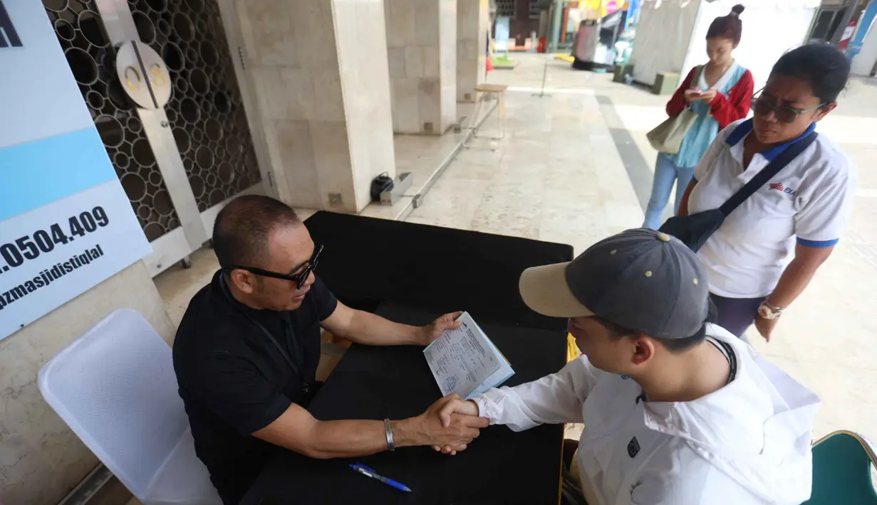 Zakat fitrah juga dapat ditunaikan dengan uang yang nilainya disetarakan dengan harga beras atau makanan pokok seberat 2,5 kg/3,5 liter atau yang biasa dikonsumsi sehari-hari. Tampak dalam foto, petugas Unit Pengelola Zakat (UPZ) melayani pembayaran zakat, fidyah, kafarat, infaq, dan shadaqah di teras Masjid Istiqlal, Jakarta, Minggu 15 Maret 2026. (Kapanlagi.com/Budy Santoso)