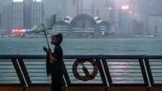Payung seorang wanita tertiup angin kencang saat Topan Saola melanda Hong Kong, Jumat (1/9/2023). Sebagian besar Hong Kong dan wilayah lain di Tiongkok selatan hampir terhenti dengan aktivitas kelas-kelas dan penerbangan dibatalkan ketika Topan Saola mendekat. (AP Photo/Daniel Ceng)