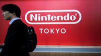 Seorang pria berjalan melewati logo Nintendo Co. Jepang yang dipajang di toko baru Nintendo di Tokyo, 19 November 2019. Nintendo akan meresmikan toko pertamanya di ibu kota Jepang tersebut pada pekan ini. (Behrouz MEHRI/AFP)