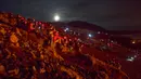 Orang-orang menyaksikan aliran lahar dari letusan gunung berapi di Semenanjung Reykjanes, barat daya Islandia, Senin (29/3/2021). Letusan gunung berapi tersebut masih menarik ribuan orang yang berharap untuk mendekati aliran lahar. (AP Photo/Marco Di Marco)