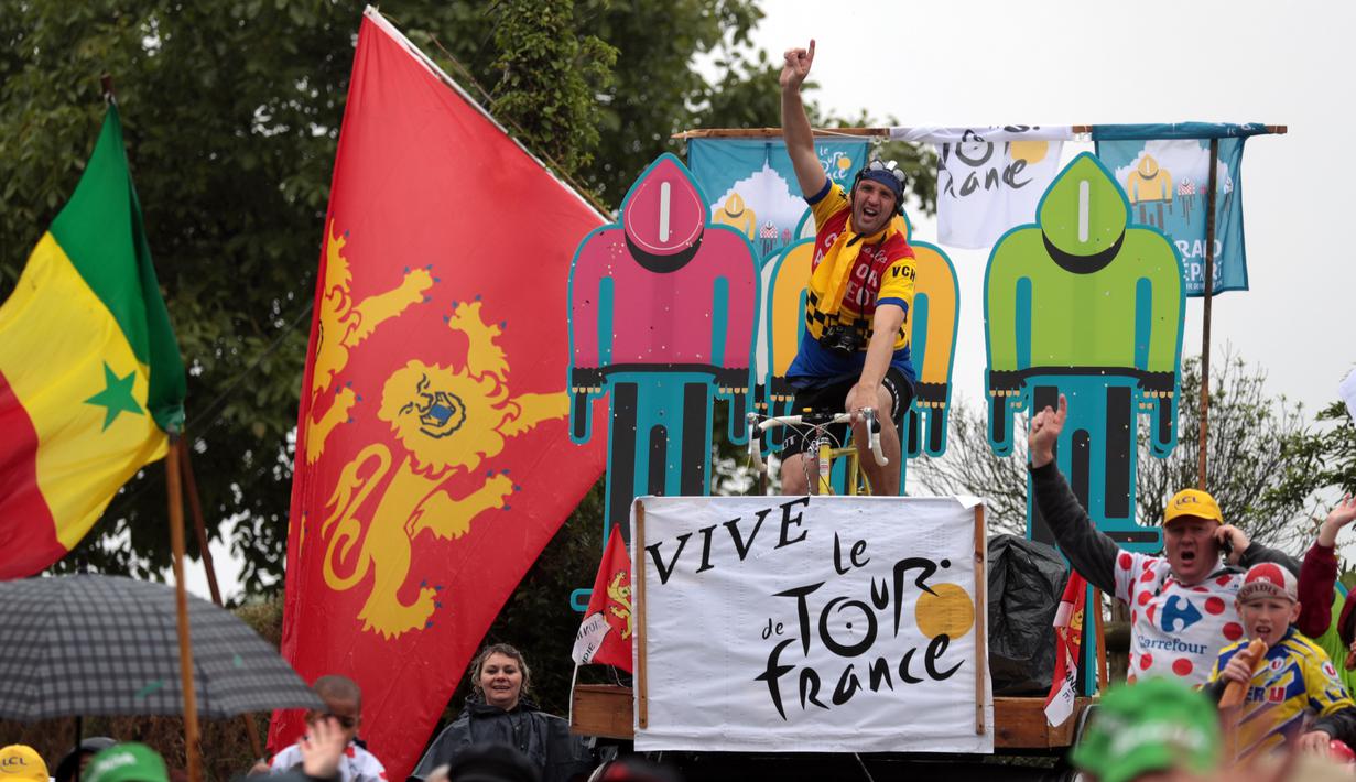 Seorang penonton bergaya ala pebalap saat menyambut kehadiran para peserta di Etape 2 Tour de France antara Saint-Lo dan Cherbourg-en-Cotentin, (3/7/2016). (AFP/Kenzo Tribouillard)