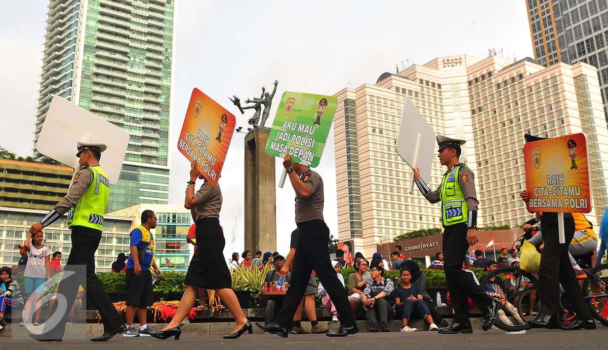Anggota Polisi berjalan sambil membawa poster saat parade busana POLRI di car free day di Bunderan HI, Jakarta (5/2). (Liputan6.com/Angga Yuniar)