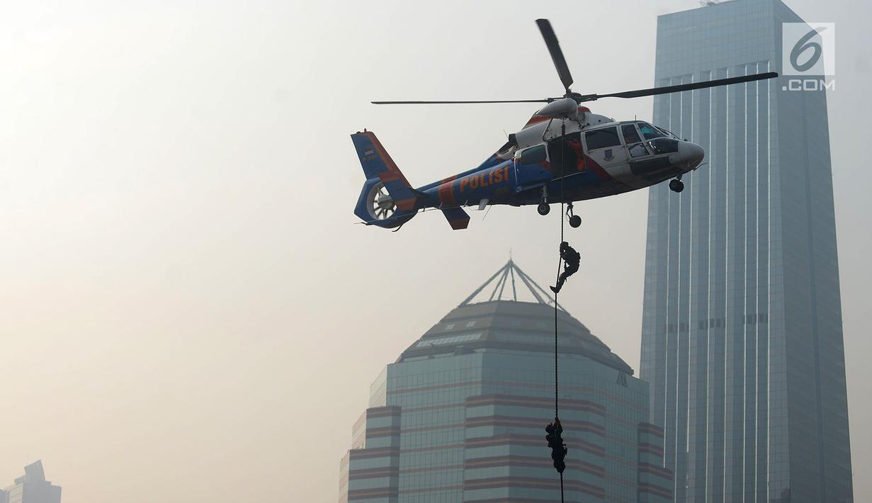 Petugas kepolisian menuruni helikopter menggunakan tali dalam apel pengamanan Asian Games 2018 di Lapangan Ditlantas Polda Metro Jaya, Jakarta, Selasa (31/7). Apel juga diikuti oleh TNI dan instansi terkait. (Merdeka.com/Imam Buhori)