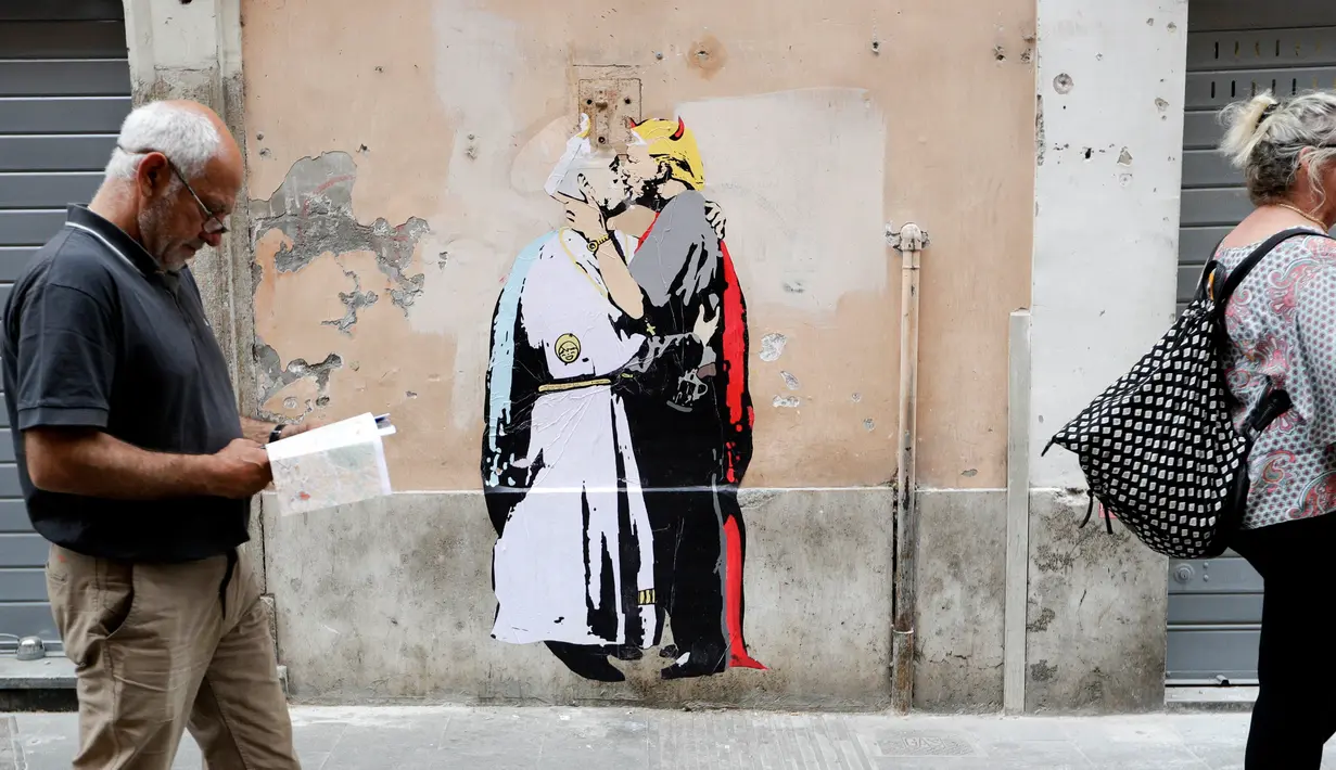 Pejalan kaki melewati mural Presiden AS, Donald Trump dan Paus Francis berciuman di sebuah dinding di Roma, Kamis (11/5). Sebuah keterangan terdapat di sisi lain dari mural yang bertuliskan, "The Good Forgives the Evil." (AP Photo/Alessandra Tarantino)