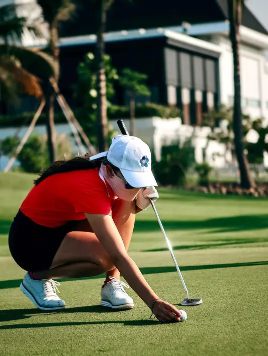 Luna Maya mengukur bola yang akan di masukan ke dalam lubang saat bermain golf. Gaya Luna Maya ini tetap stylish. (Instagram/lunamaya)