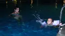 Setelah menemani anaknya bermain di playground, ibu tiga anak itu langsung membawa buah hatinya ke Nusa Dua Beach, Bali. Di sana, mereka merasakan sensasi berenang di malam hari. (Galih W. Satria/Bintang.com)