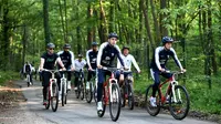 Pemain timnas Prancis mengendarai sepeda pada latihan untuk persiapan Piala Dunia 2018 di sekitar markas latihan, Clairefontaine-en-Yvelines, Rabu (23/5). Mereka kompak berjaket Timnas Prancis model terbaru lengkap dengan helm pelindung. (AFP/FRANCK FIFE)