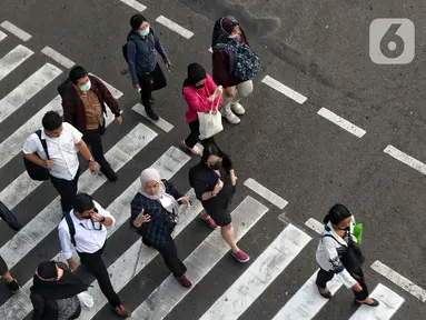 Sejumlah pekerja menyeberang jalan saat jam pulang kerja di kawasan Thamrin, Jakarta, Selasa (11/7/2023). Pemerintah Provinsi (Pemprov) DKI Jakarta menyebut penerapan pengaturan jam masuk kerja bagi perusahaan swasta di DKI Jakarta hanya bersifat imbauan. (Liputan6.com/Angga Yuniar)
