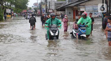 Warga berusaha melintasi genangan air ketika banjir merendam Jalan KH. Hasyim Ashari, Tangerang, Banten, Sabtu (16/7/2022). Akibat luapan kali angke ruas jalan yang menghubungkan Tangerang-Jakarta itu terputus akibat banjir. (Liputan6.com/Angga Yuniar)