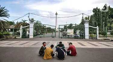 Warga menikmati sore hari di depan gerbang masuk Monumen Nasional (Monas), Jakarta, Minggu (15/11/2020). Meski masih ditutup untuk umum sejak awal pandemi Covid-19, kawasan Monas tetap ramai dikunjungi warga untuk sekadar mengisi akhir pekan. (merdeka.com/Iqbal S Nugroho)