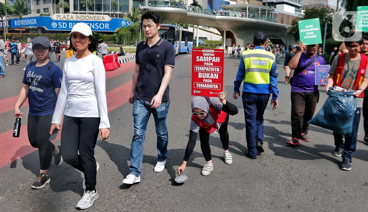 Relawan 'Operasi Semut' dari berbagai komunitas mengajak para pengunjung CFD untuk memungut sampah di Kawasan Bundaran HI, Jakarta, Minggu (19/2/2023). Aksi memungut sampah tersebut merupakan kampanye memperingati 'Hari Peduli Sampah Nasional dan Hari Bersih Indonesia 2023'. (Liputan6.com/Angga Yuniar)