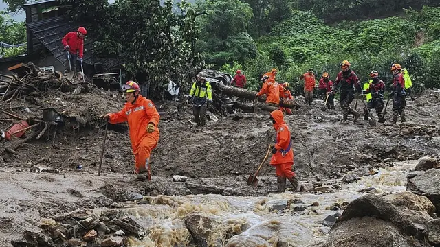 Petugas penyelamat mencari orang-orang di rumah-rumah yang ambruk menyusul jalur darat yang disebabkan oleh hujan lebat Yecheon, Korea Selatan. (AP)