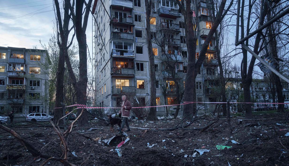 Seorang wanita bersama seekor anjing berjalan di antara reruntuhan rumah yang rusak akibat serangan Rusia di daerah pemukiman, Kyiv, Ukraina, pada Kamis 16 April 2026. Rusia kembali melancarkan salah satu serangan udara terbesarnya ke Kyiv, Ukraina. (AP Photo/Evgeniy Maloletka)