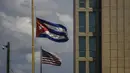 <p>Sebuah bendera Kuba terlihat di sebelah bendera Amerika Serikat di luar kedutaan besar AS di Havana, Selasa (17/5/2022). Pemerintahan Presiden AS, Joe Biden mengumumkan akan melonggarkan pembatasan atas pengetatan yang diberlakukan selama pemerintahan Donald Trump terhadap Kuba dan mencabut batas saat ini $1.000 per kuartal yang dapat dikirim imigran kepada anggota keluarga yang masih tinggal di pulau itu. (AP Photo/Ramon Espinosa)</p>