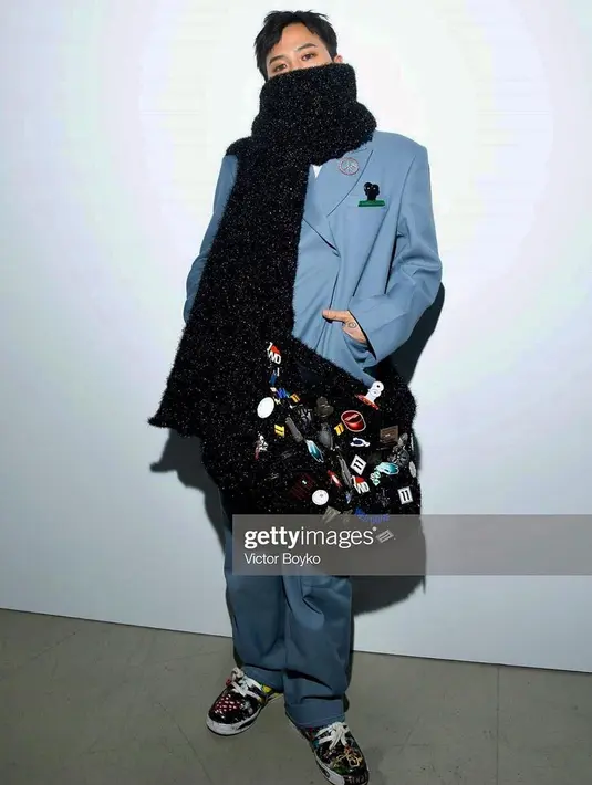 Menghadiri acara fashion, G-Dragon tampil mengenakan set oversized blazer dengan celana yang bernuansa biru muda. Sebagai statement, ia menambahkan syal hitam yang besar, yang jika dililitkan bisa menjadi sling bag dengan berbagai patch. Foto: Instagram.