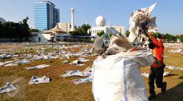 Pemulung memasukkan lembaran koran bekas usai pelaksanaan salat Idul Fitri 1436 H di Lapangan Masjid Agung Al Azhar, Jakarta, Jumat (17/7/2015). Sisa koran bekas menjadi rejeki tersendiri bagi para pemulung. (Liputan6.com/Yoppy Renato)