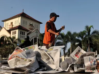 Petugas membersihkan sampah koran di ruas Jalan Jatinegara Barat, Jakarta, Jumat (17/7/2015). Lembaran koran bekas ditinggalkan begitu saja pasca pelaksanaan salat Hari Raya Idul Fitri 1436 H. (Liputan6.com/Johan Tallo)