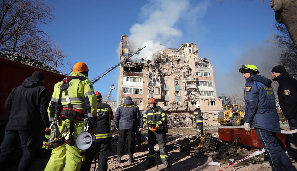 Satu gedung terbakar, sementara lantai atas bangunan lainnya hancur total. Tampak dalam foto, petugas penyelamat memadamkan kebakaran di sebuah gedung perumahan yang rusak akibat serangan Rusia di Ternopil, Ukraina, pada Rabu 19 November 2025. (AP Photo/Rostyslav Kovalchuk)