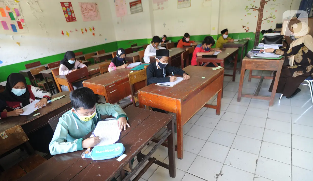Guru mengawasi murid kelas V saat menjalani ujian Penilaian Akhir Semester (PAS) tahun pelajaran 2020/2021 di Madrasah Ibtidayah (MI) Assu'ada di Pancoran Mas, Depok, Jawa Barat, Selasa (1/12/2020). Ujian dilaksanakan dengan menerapkan protokol kesehatan dalam kelas. (merdeka.com/Arie Basuki)