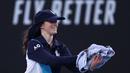 Seorang ball girl menangkap seekor serangga yang memasuki lapangan ketika laga Australia Open 2024 antara petenis Inggris, Emma Raducanu melawan petenis Amerika Serikat di Melbourne Park, Melbourne, Australia, Selasa (16/01/2024). (AFP/David Gray)