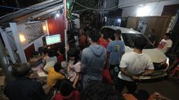 Sejumlah warga terpaksa bangkit dari duduknya saat mobil melintas di lokasi nobar pertandingan Timnas Indonesia melawan Bahrain dalam pertandingan Grup C putaran ketiga Kualifikasi Piala Dunia 2026 zona Asia di kawasan Menteng Jaya, Jakarta, Selasa (25/5/2025). (Bola.com/M Iqbal Ichsan)