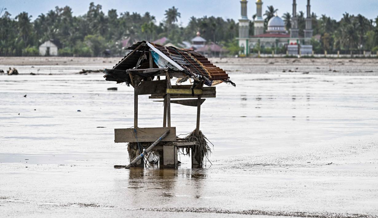 Kerusakan juga terjadi pada jaringan irigasi yang mempersulit pengairan, bahkan setelah lumpur dibersihkan, sementara lumpur tebal menyulitkan pemulihan lahan. Tampak foto lahan pertanian yang berada di samping masjid terendam lumpur setelah banjir bandang di Meureudu, Kabupaten Pidie Jaya, Provinsi Aceh, pada Senin 8 Desember 2025. (Chaideer MAHYUDDIN/AFP)