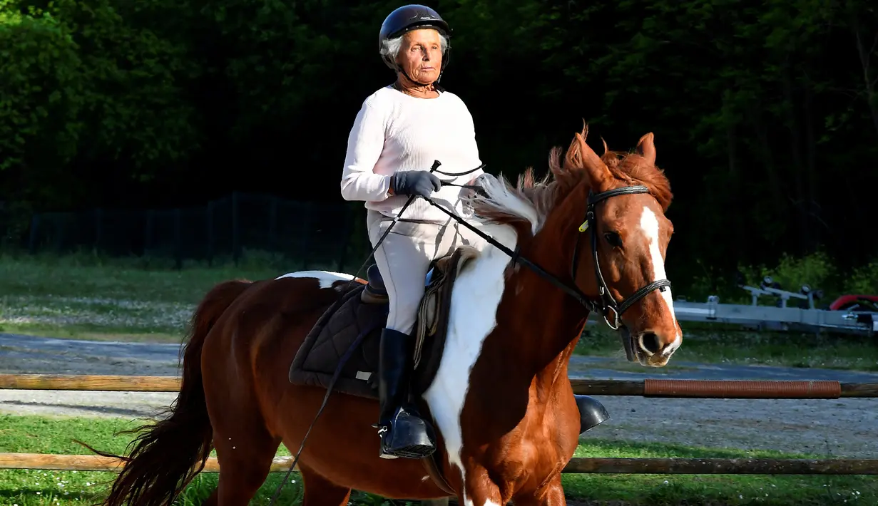 Nicole de Villeneuve (89)menunggangi kuda selama sesi pelatihan stabil berkuda di Arcachon, Prancis (24/4). Setelah berhenti berkuda selama 30 tahun, Nicole de Villeneuve baru saja memenangkan pertunjukan kuda pertamanya. (AFP Photo/Georges Gobet)